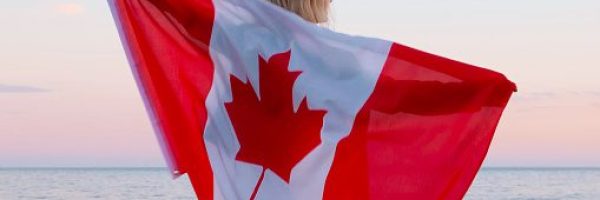 Back view woman waving national canada flag outdoors ocean sea sunset at summer - Canada day, country, patriotism, independence day 1th july